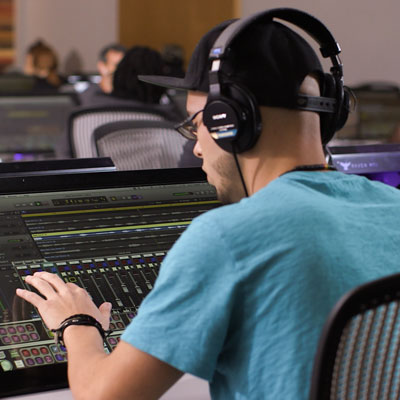 A student working on a mixing console in the studio
